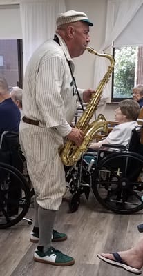 A musician playing saxophone for residents in a common area