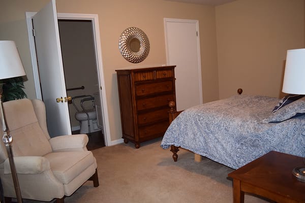 A well-furnished private resident room with a bed and chair
