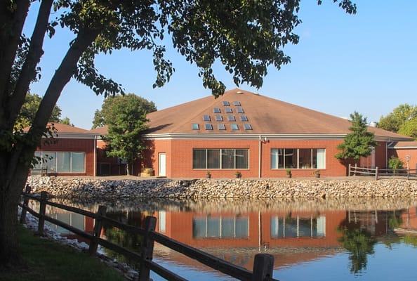 Exterior view of a senior living facility by a pond