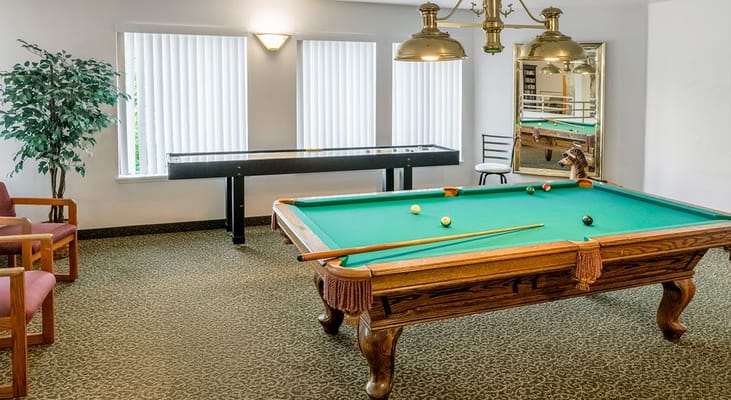 Billiards table in a recreational area with seating and natural light
