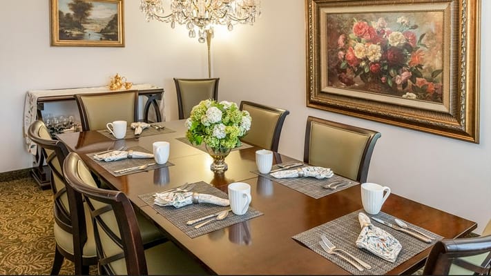 A dining table set for a meal with floral centerpiece and tableware.