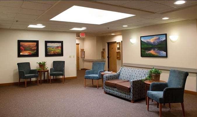 Lounge area with chairs, a couch, and paintings on the wall
