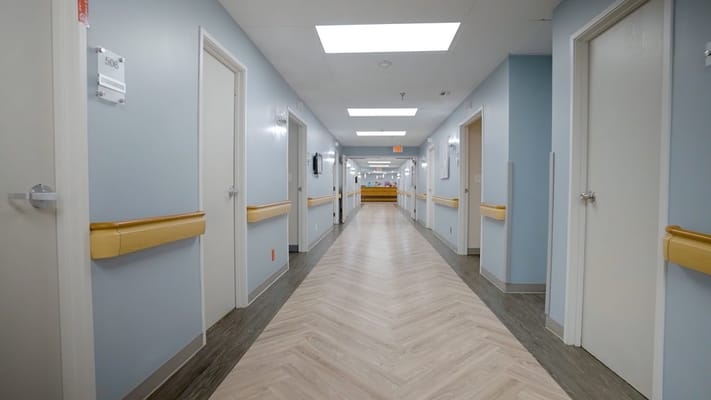 Brightly lit hallway with doors on either side at Spring Valley Assisted Living