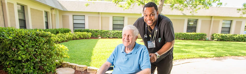 Smiling senior man in a wheelchair with a caregiver in a garden setting