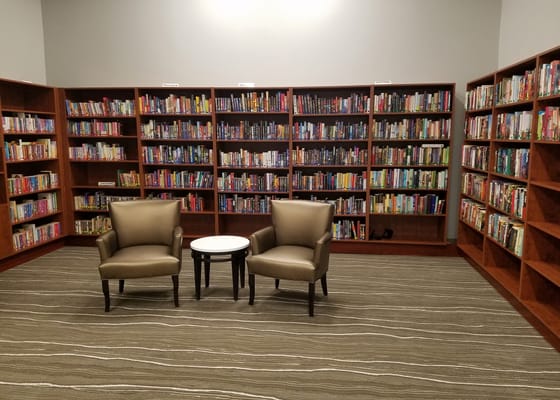 Two armchairs and a small table in a library surrounded by bookshelves