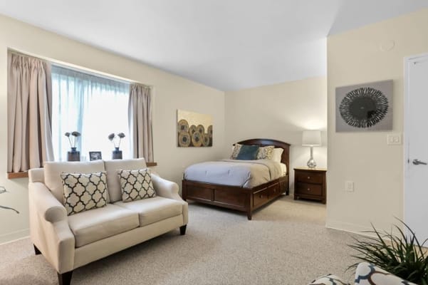 Bright and comfortable bedroom with a bed, sofa, and window