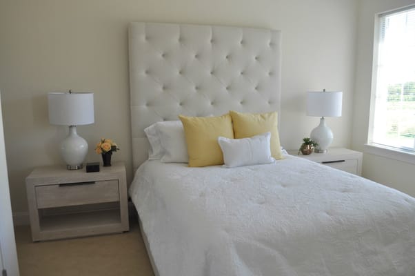 A well-decorated bedroom featuring a bed with decorative pillows, bedside tables, and lamps.