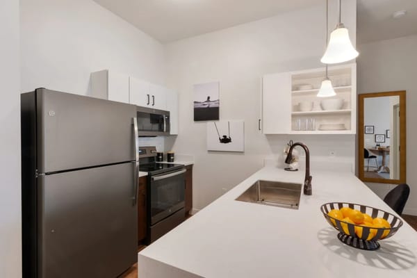 Contemporary kitchen featuring stainless steel appliances and a bowl of fruit