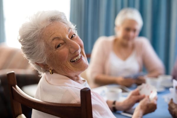 Senior woman smiling while playing cards with others