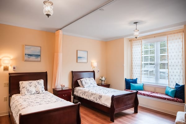 A twin bedroom with two beds, a nightstand, and a window nook.