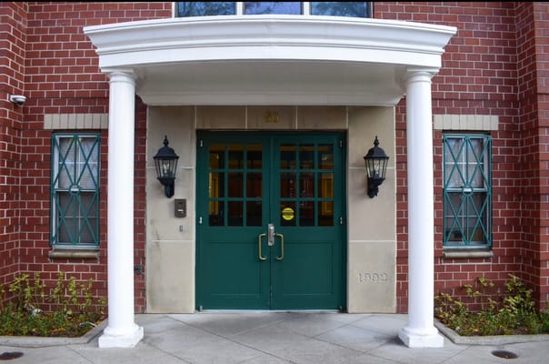 Front entrance with green doors and brick facade