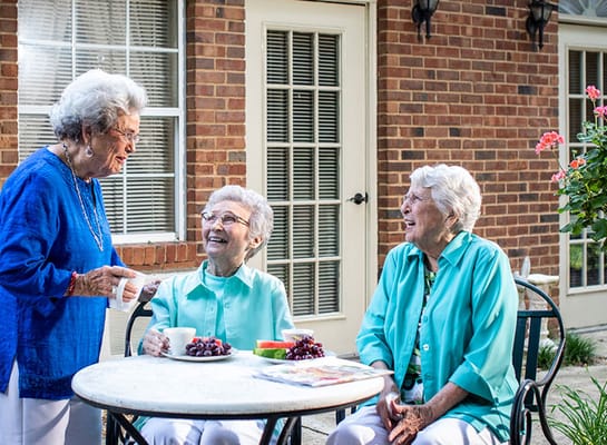 Three residents enjoying tea and snacks in a garden
