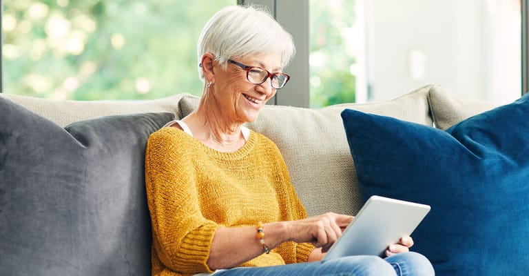 Senior woman engaging with a tablet in a cozy setting.