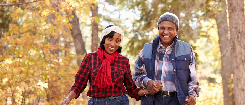Two seniors walking together in a forested area