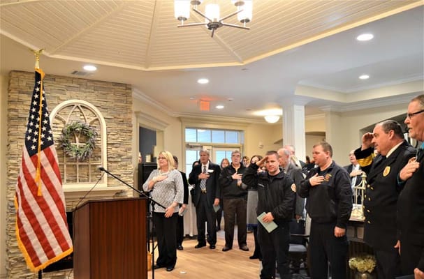 Residents and staff salute during a ceremony indoors