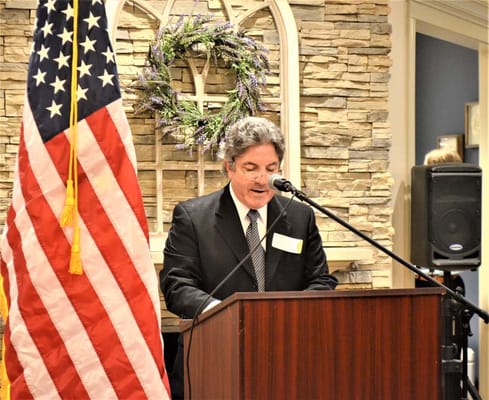 Speaker addressing audience with an American flag in background