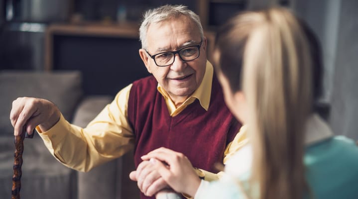 A senior man talking with a staff member in a cozy setting