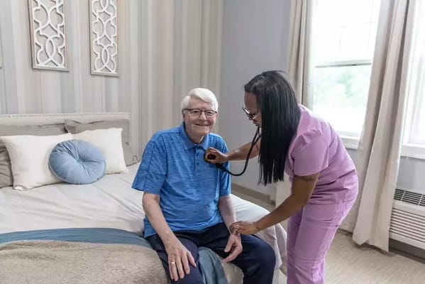 A caregiver checking a resident's vitals in their room