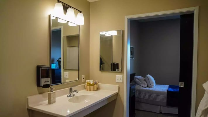 Bathroom sink area with a bedroom in view