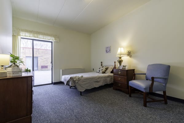 A private resident room with a bed and chair