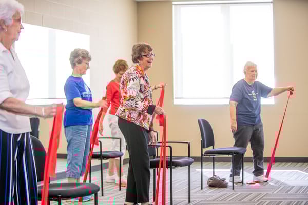 Residents participating in a seated exercise class with red bands