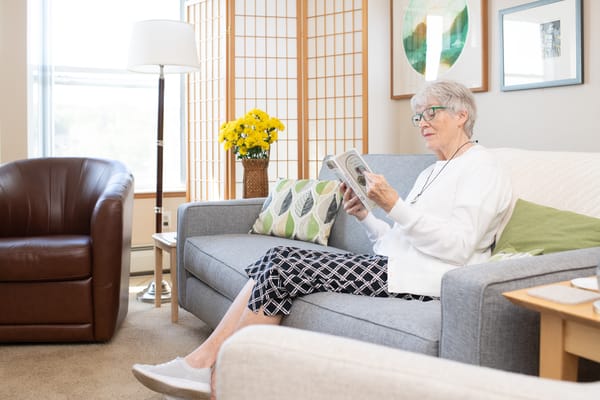 A senior resident reading a book in a cozy lounge
