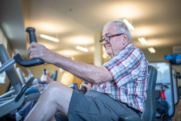 Senior resident exercising on a stationary bike in a fitness area