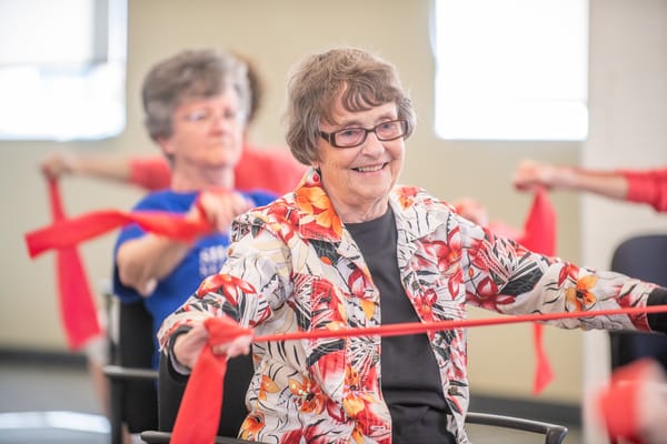 Residents participating in a stretch exercise class with red bands