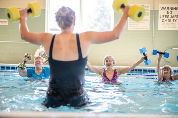Residents participating in an aquatic fitness class using weights