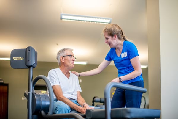 Staff assisting a senior resident in a fitness area