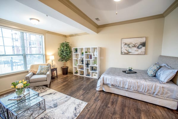 Brightly furnished resident room with a bed and seating area