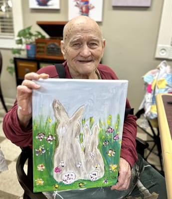 Elderly resident holding a painting of rabbits