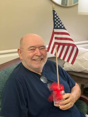 Elderly man smiling with a small American flag.