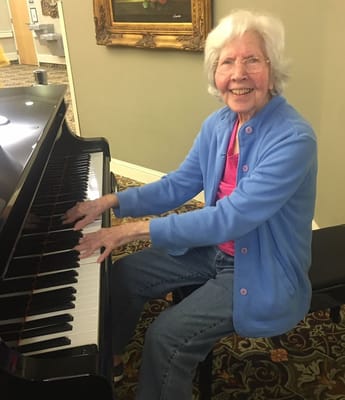 Resident playing piano in a bright common area