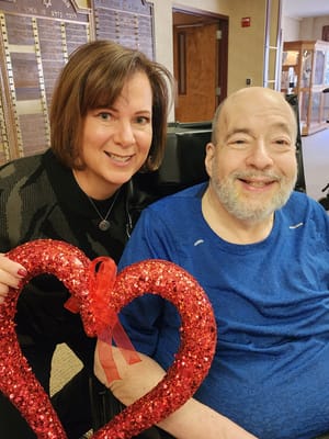 Staff member and resident celebrating with a heart decoration