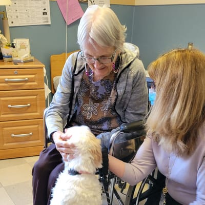 A resident interacting with a staff member and a dog