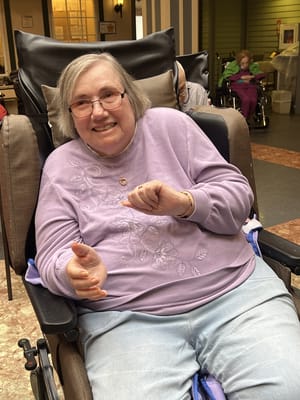Resident smiling in a wheelchair in the common area