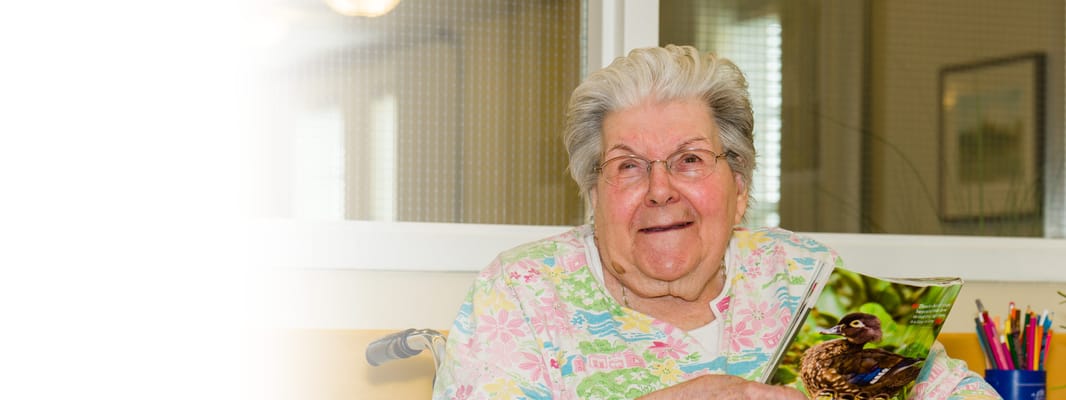 Resident smiling with a nature magazine in activity room