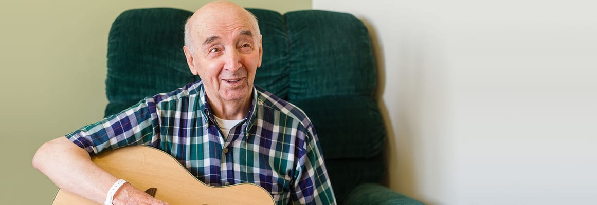 Senior resident playing guitar in a cozy lounge