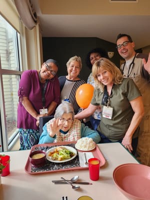 Residents enjoying a meal with staff in a dining area