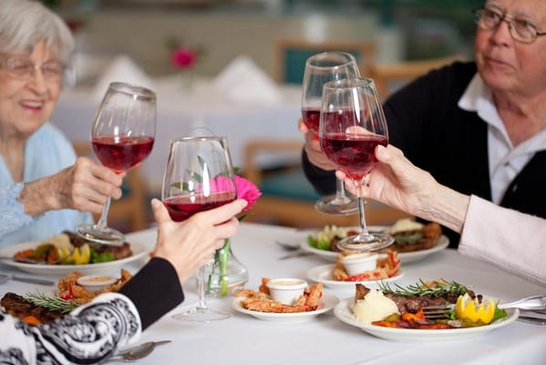Residents toasting with drinks at a dining table