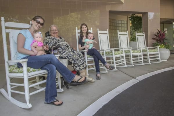 Residents and family members enjoying rocking chairs outside