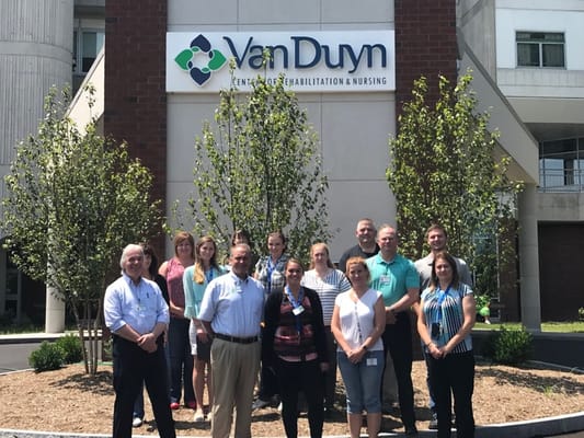Staff members posing outside the Van Duyn Center building
