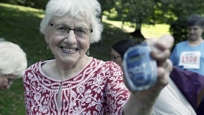 A resident smiling and holding a prize outdoors