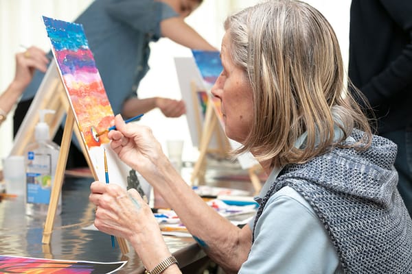 A resident painting during an art activity in a bright room