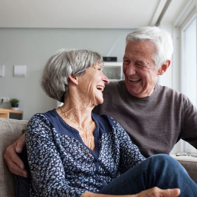 Two seniors laughing together in a cozy indoor setting