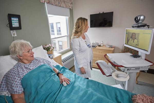 Resident video calling a doctor with staff assistance