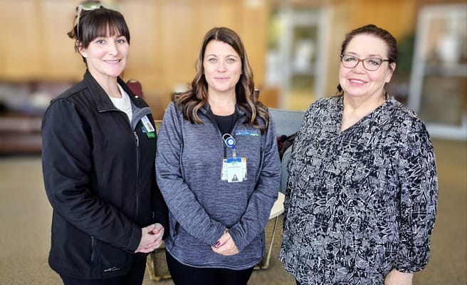 Three staff members smiling together in a lobby area