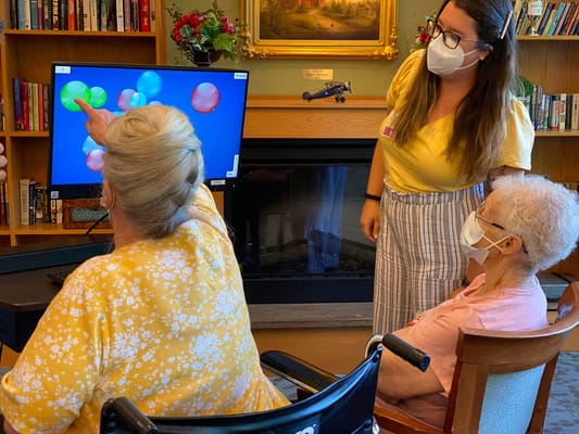 Residents engaging with a staff member in an activity room