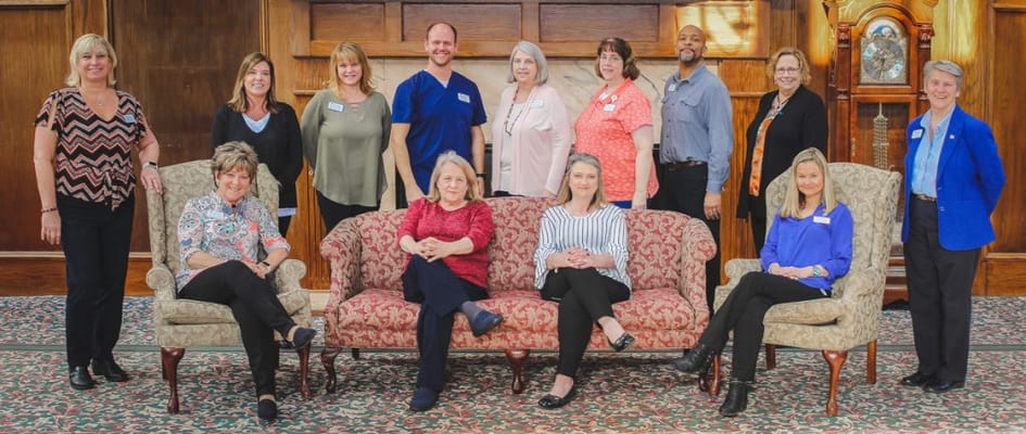 Staff members posing in a common area with floral sofas